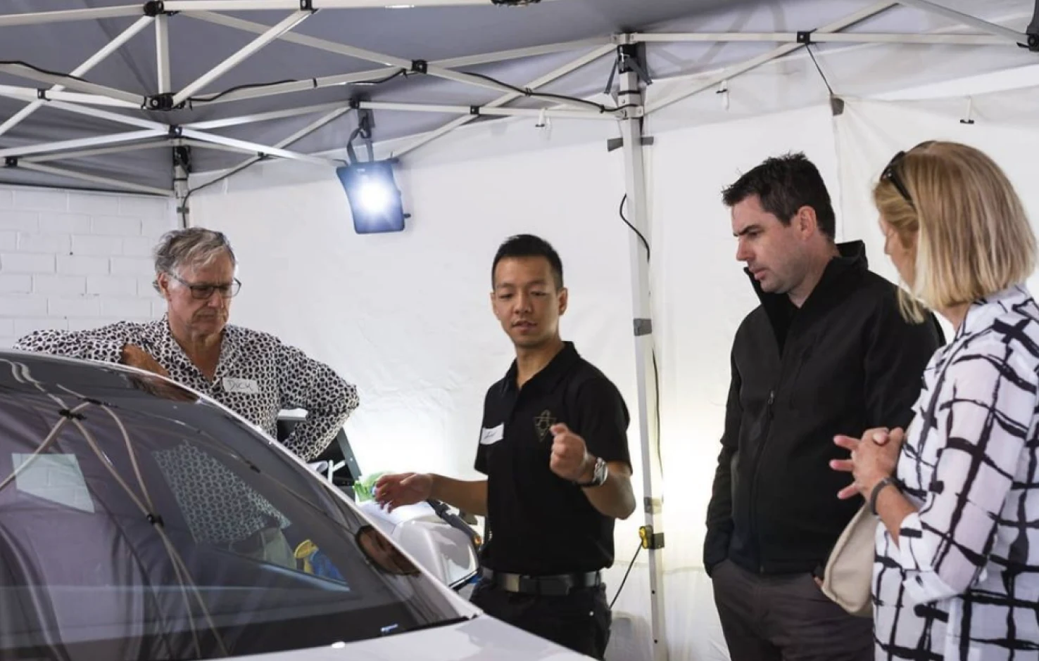 Affinesse team walking guests around a car at an event