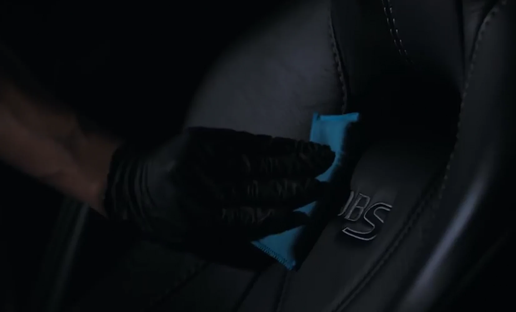 Gloved hand wiping coating onto a leather seat